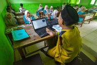 Untung, seorang guru difabel, mengoperasikan laptop dengan kaki kanannya saat mengajar di Madrasah Ibtidaiyah (MI) Miftahul Ulum Batang-batang, Sumenep, Madura, Jawa Timur, Rabu (19/10/2022). Saat ini jumlah tenaga kerja aktif yang terdaftar di BPJAMSOSTEK mencapai 35 juta pekerja, sedangkan target untuk tahun 2026 BPJAMSOSTEK bisa memberikan perlindungan jaminan sosial kepada 70 juta pekerja.